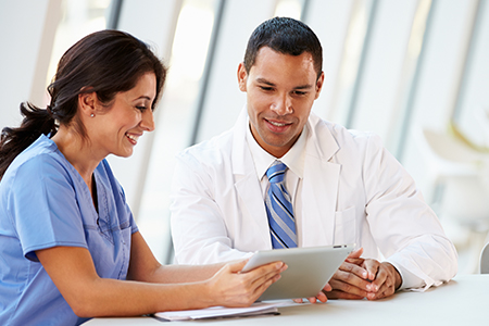 Male medical professional sitting at his desk working on a digital tablet