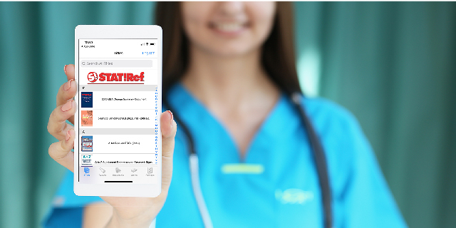 Young woman wearing a backpack, sitting high atop a building with city skyline back-drop working on a laptop
